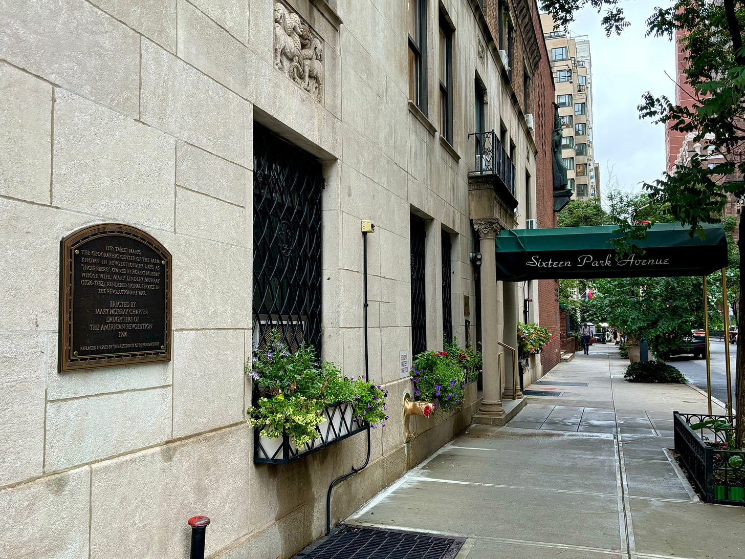 Facing east on the corner of 35th and Park, looking at the green awning for Sixteen Park Avenue. A plaque is visible on the side of the building.