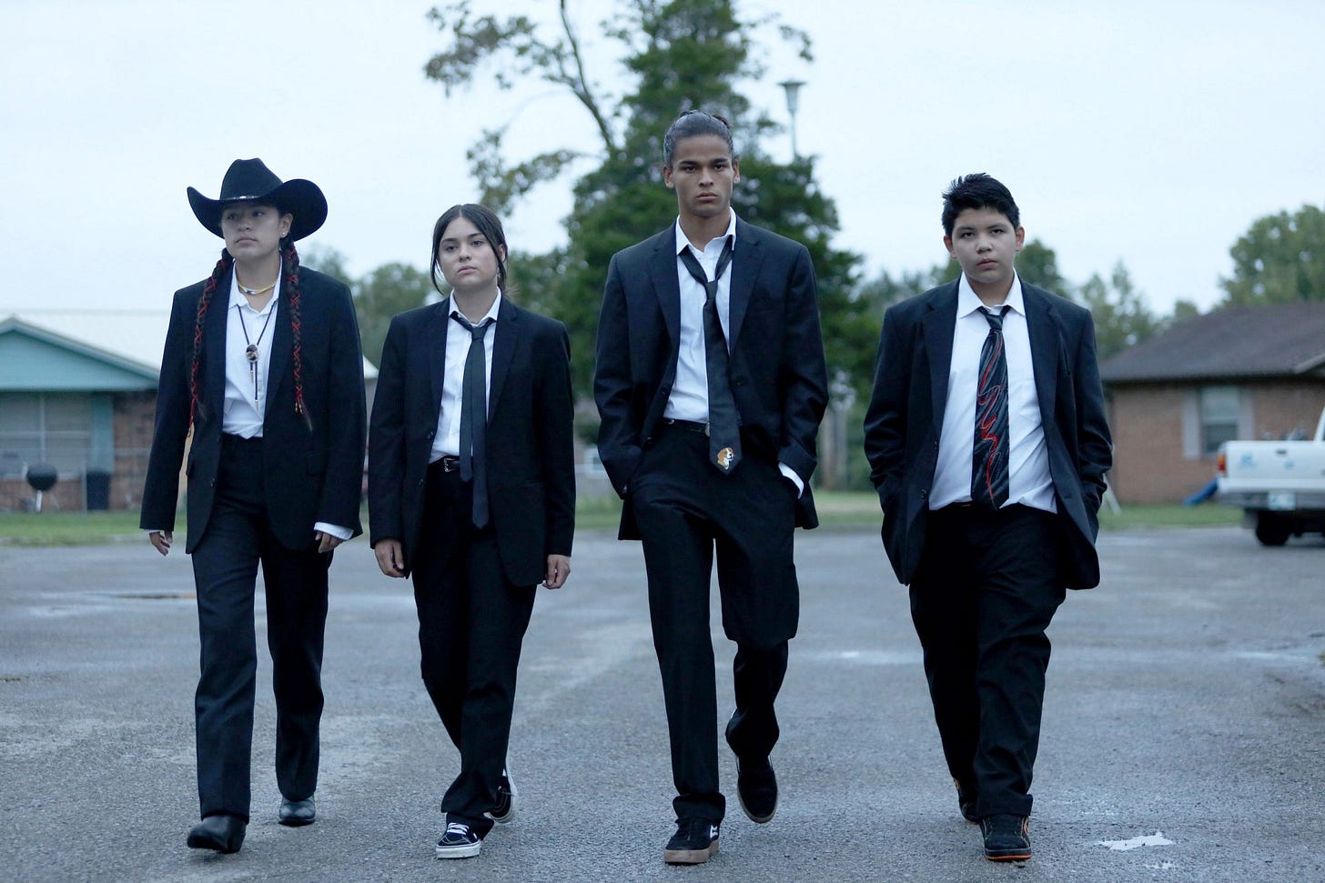 The four main characters of Reservation Dogs walk toward the camera, dressed in snazzy suits. The four main characters of Reservation Dogs walk toward the camera, dressed in snazzy suits.