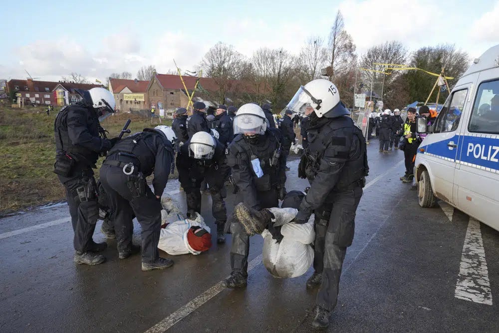 A police officers clear a blocked road at the village Luetzerath near Erkelenz, Germany, Wednesday, Jan. 11, 2023. Police have entered the condemned village in, launching an effort to evict activists holed up at the site in an effort to prevent its demolition to make way for the expansion of a coal mine. (AP Photo/Michael Probst)