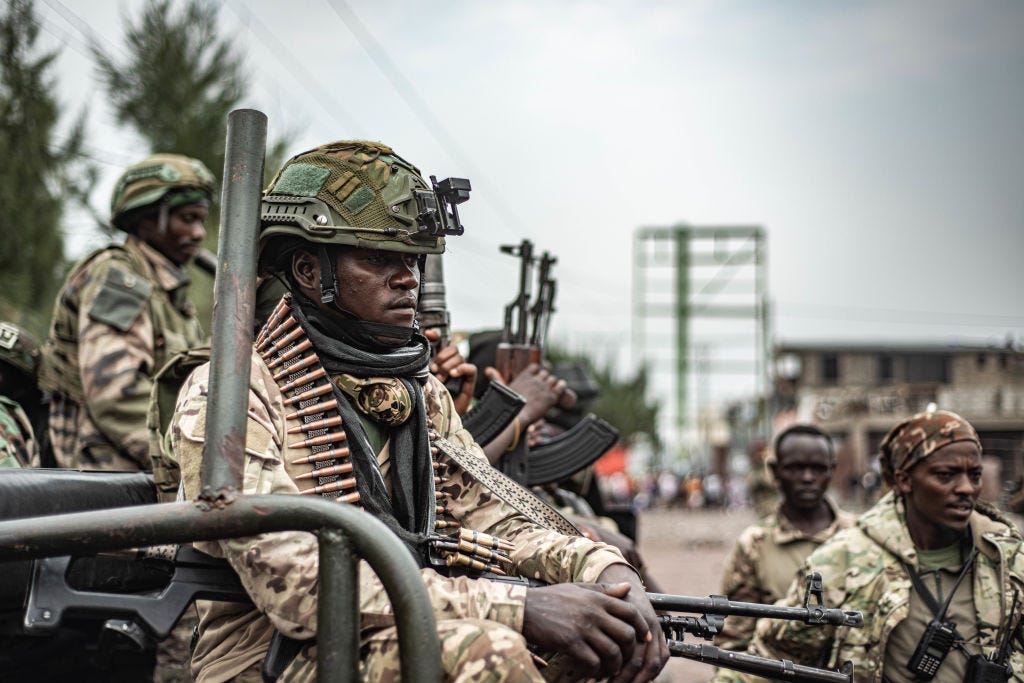 M23 fighters stand nearby as an estimated 2400 Congolese (FARDC) soldiers surrendered en masse to M23 forces at the Stade de l'Unite on January 30, 2025 in Goma, Democratic Republic of Congo. The Rwanda-backed M23 rebel group has seized control Goma, in Eastern Congo, and are reportedly advancing south.