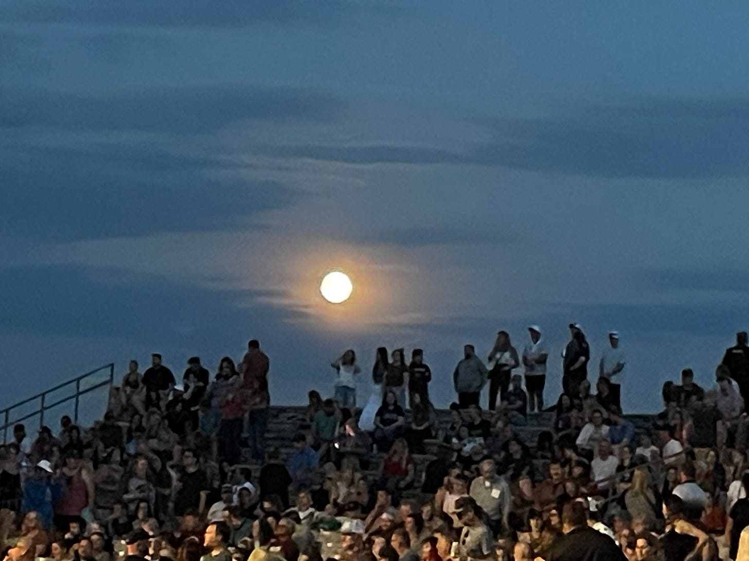 The full moon shines above concertgoers