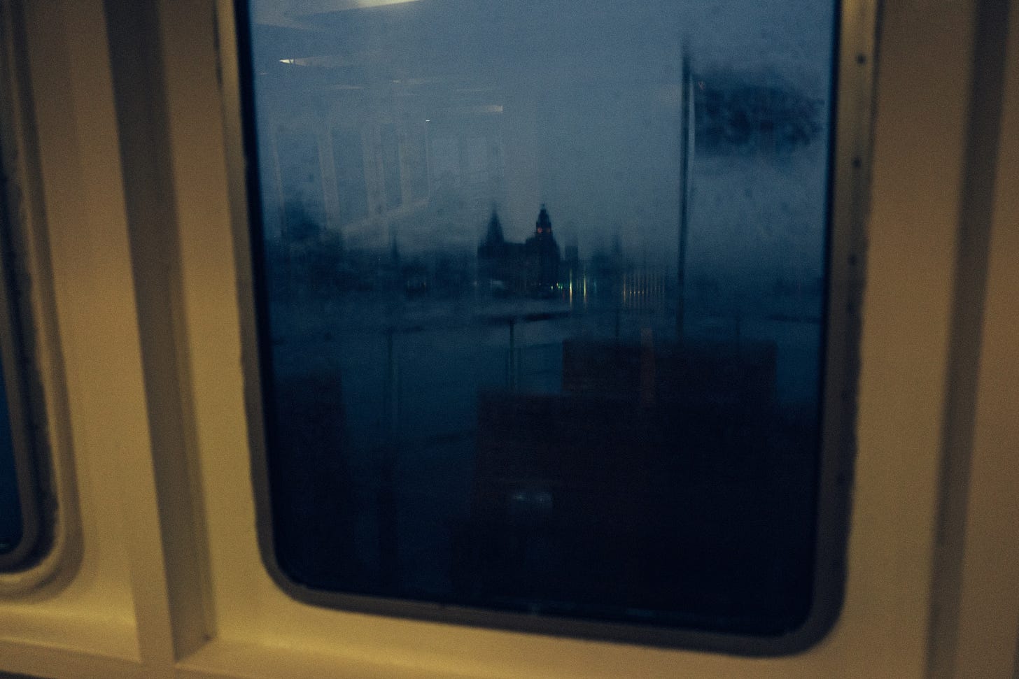 At dusk, through a rain-soaked window on the Mersey Ferry, the Liver Building appears.