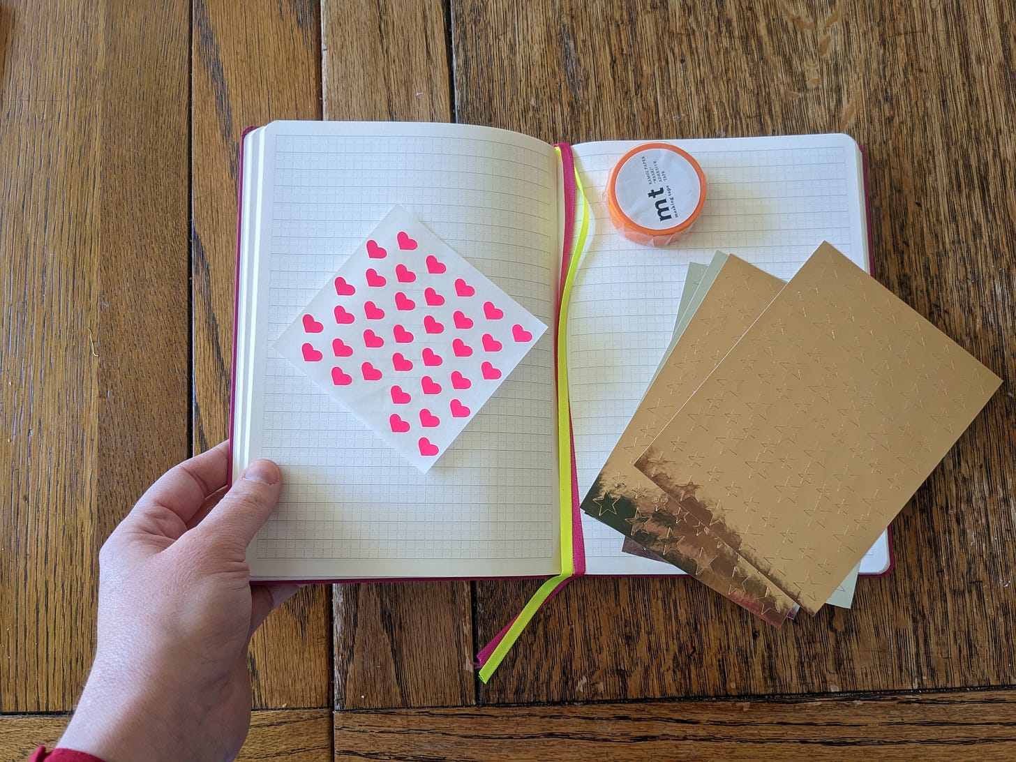 An open notebook on a table with some star and heart stickers