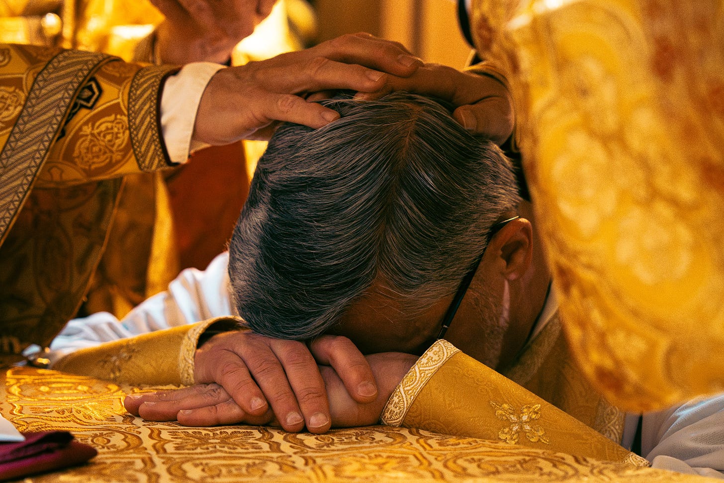 Father Robert Pipta rests his head on the altar at his episcopal ordination, Nov. 8, 2023.