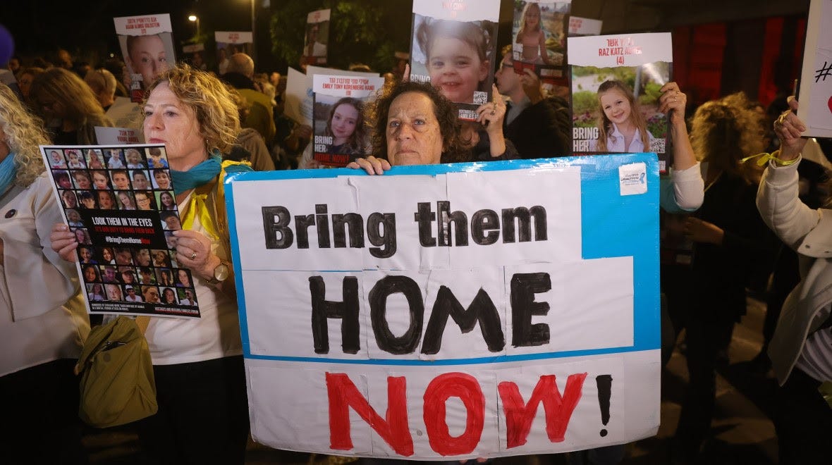 A woman holds a placard with the words "Bring them home now".