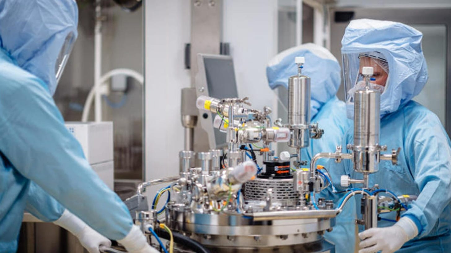 Lab workers in protective gear prepare a section of the production line for the mRNA vaccine