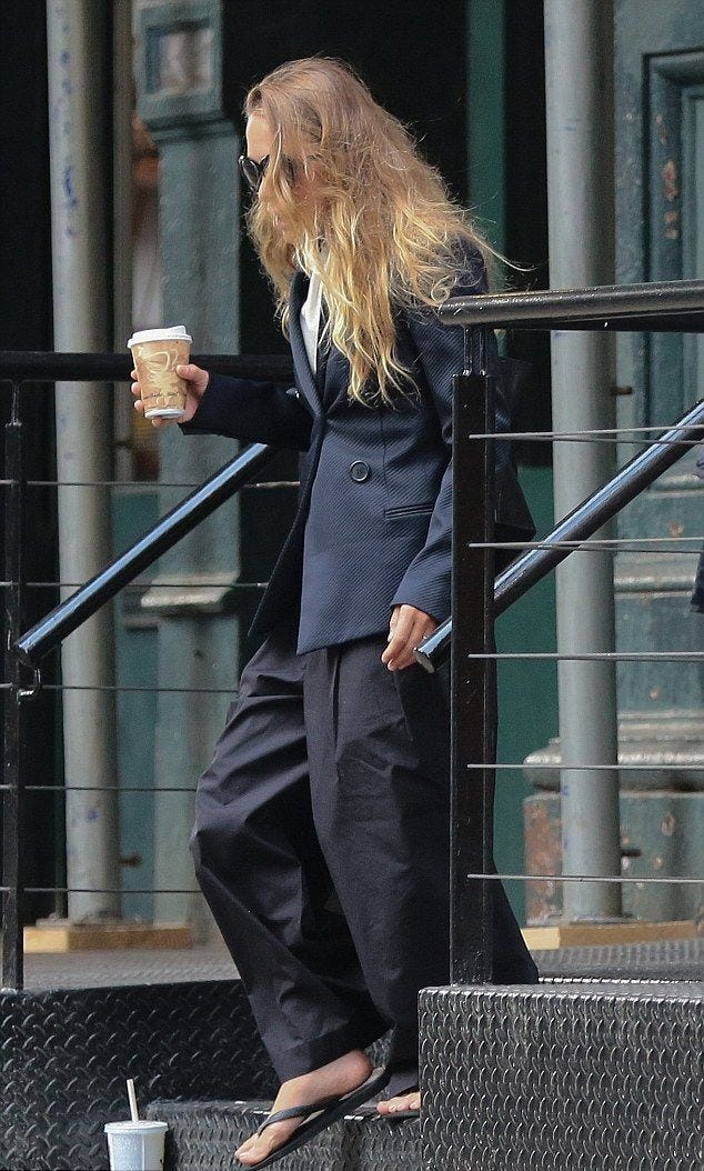 This may contain: the blonde woman is walking down the steps with her coffee in hand and she has long hair