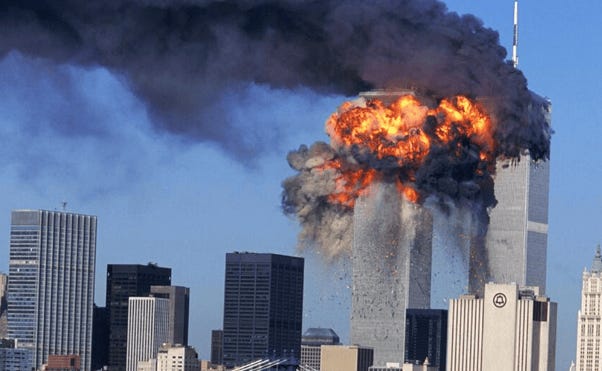 A large building with smoke and flames with World Trade Center in the background

Description automatically generated with medium confidence