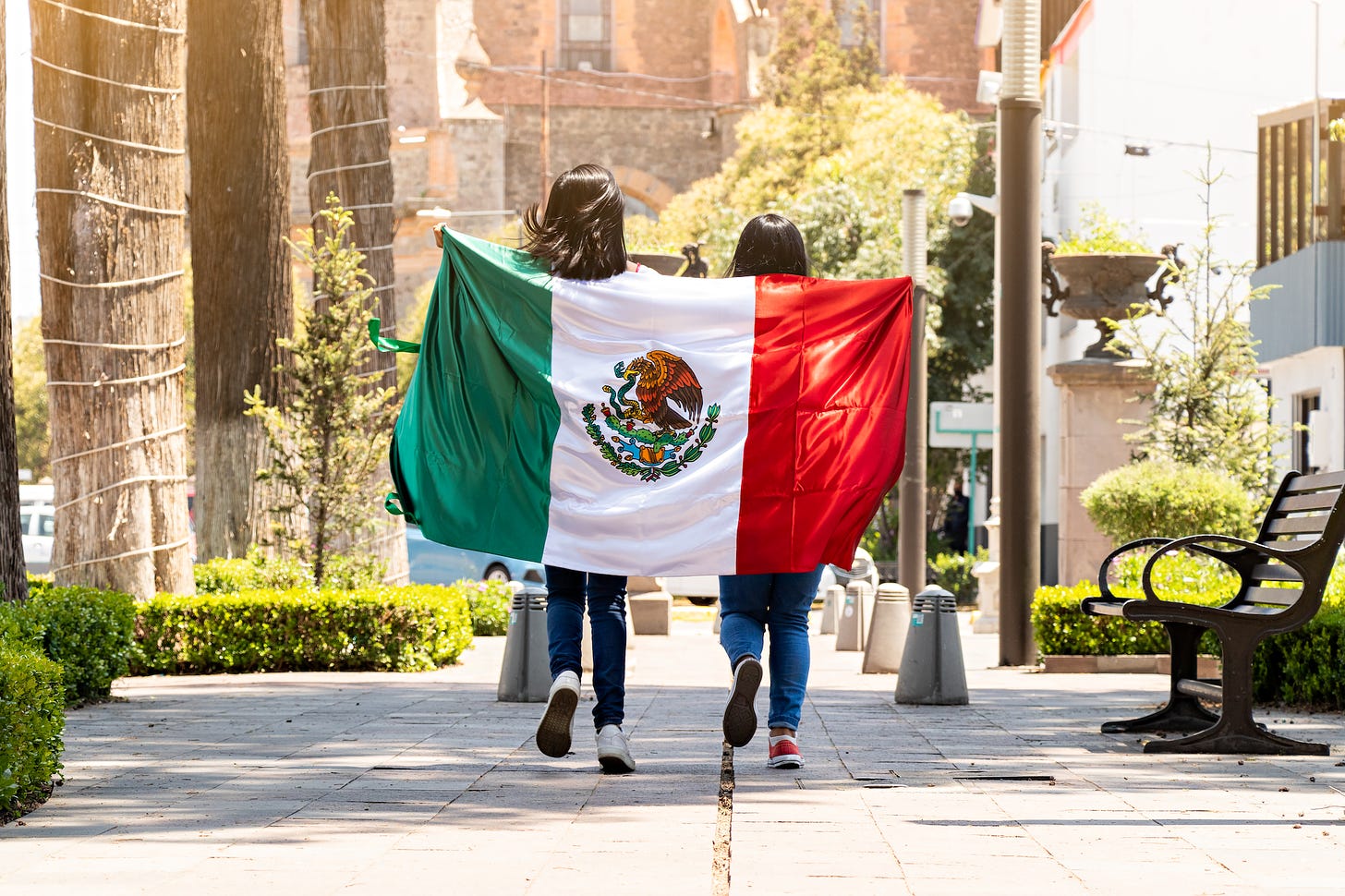 2 women carry the Mexican flag draped behind their backs