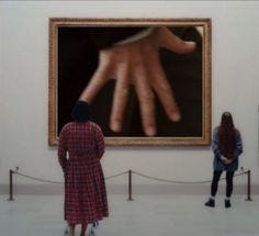 This may contain: two people standing in front of a painting with their hands on the wall and behind them is a hand print