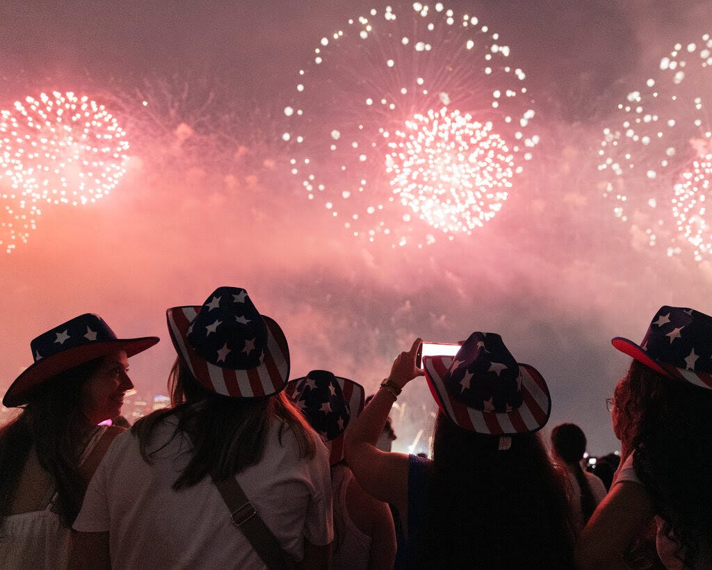 People in American flag cowboy hats watching fireworks. 