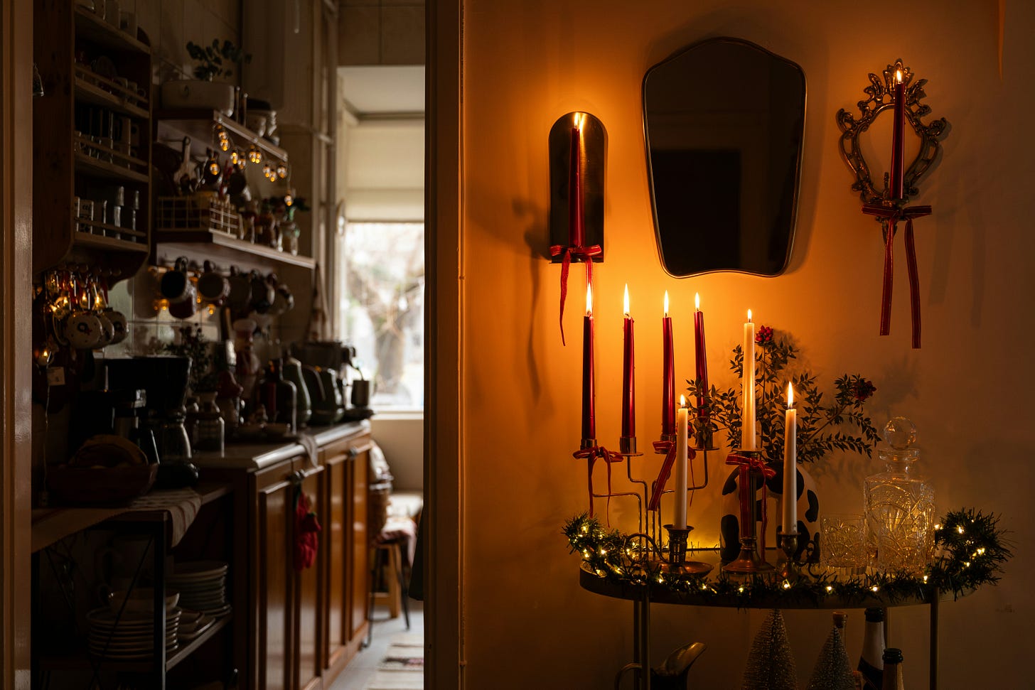A warm home area with candles on a table and a door on the left leading into the kitchen