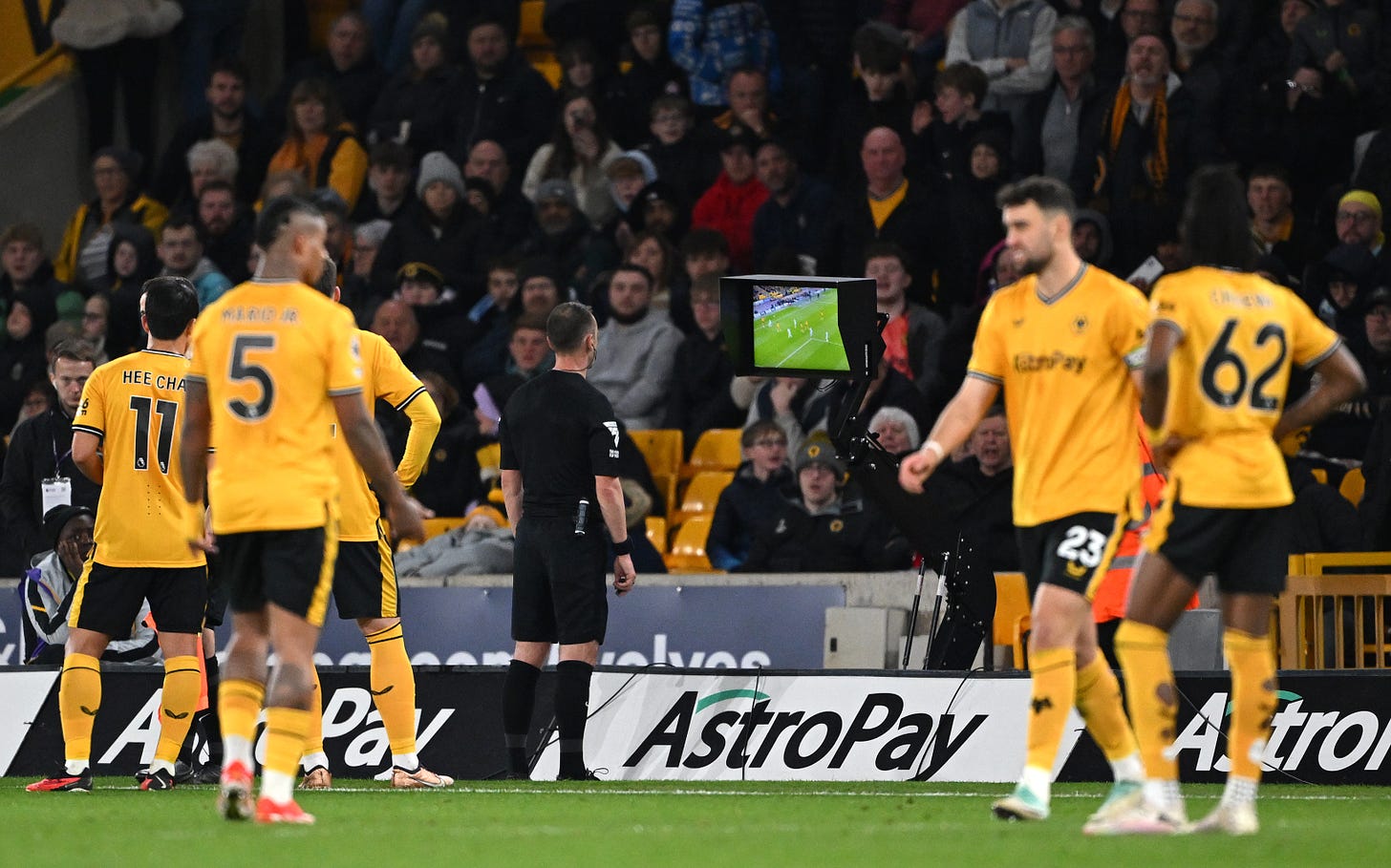 Referee Stuart Attwell pictured looking at a pitchside VAR monitor before disallowing a goal for Wolves against Bournemouth in April 2024