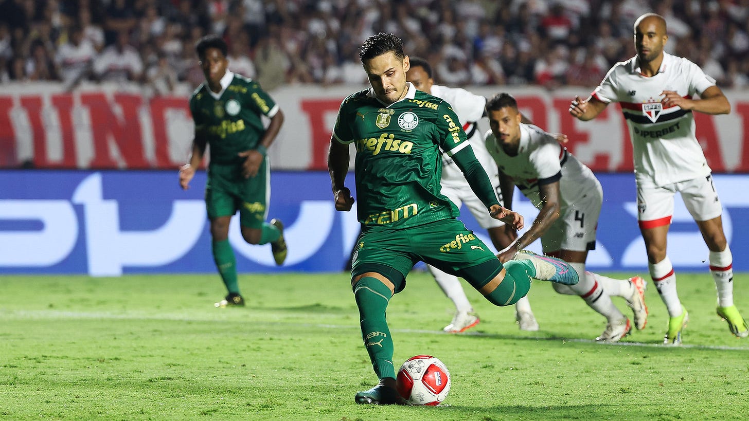  Raphael Veiga exatamente antes de cobrar de pé esquerdo o pênalti no jogo contra o São Paulo. Veste uniforme do Palmeiras, todo verde. A foto é de lado, da direita para a esquerda.