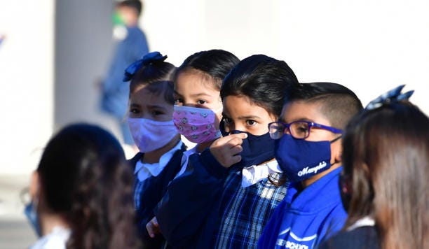 A students adjusts her facemask at St. Joseph Catholic School in La Puente, California on November 16, 2020, where pre-kindergarten to Second Grade students in need of special services returned to the classroom today for in-person instruction. - The campus is the second Catholic school in Los Angeles County to receive a waiver approval to reopen as the coronavirus pandemic rages on. The US surpassed 11 million coronavirus cases Sunday, adding one million new cases in less than a week, according to a tally by Johns Hopkins University.