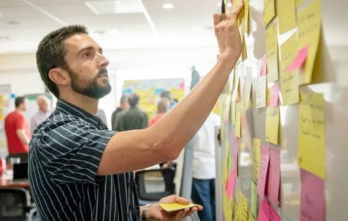 A person putting up stickies on a board during an Agile planning