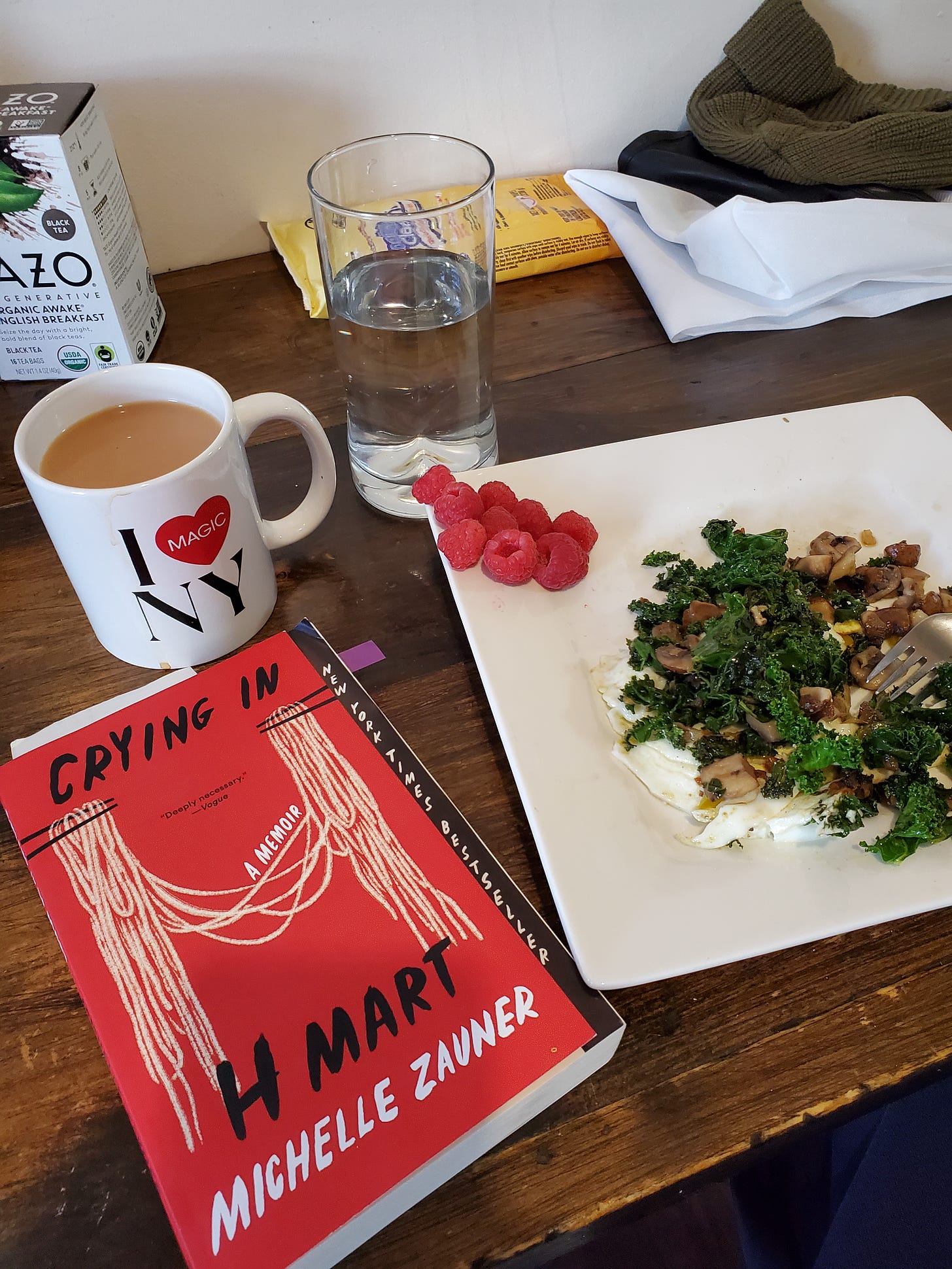 A breakfast scene shows the "Crying in H Mart" book next to a plate of eggs and greens, a cup of tea, and various other items.