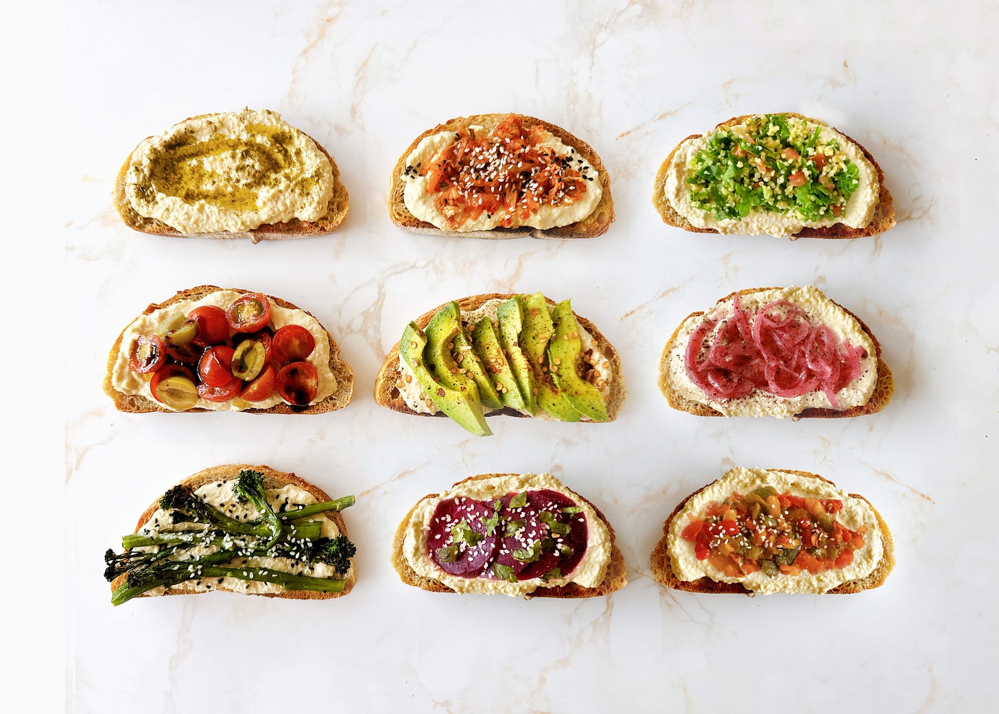 Image of 9 slices of hummus on toast with different toppings