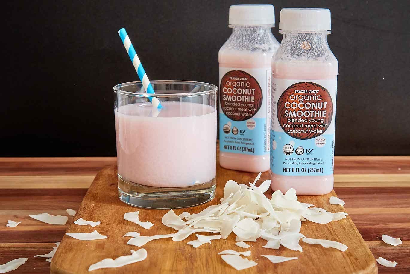 Trader Joe's Organic Coconut Smoothie; in a short glass with a paper straw, shredded coconut in foreground