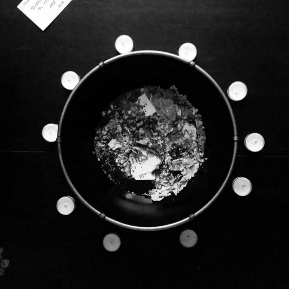 A bowl filled with ashes and surrounded by ten tea candles in black and white