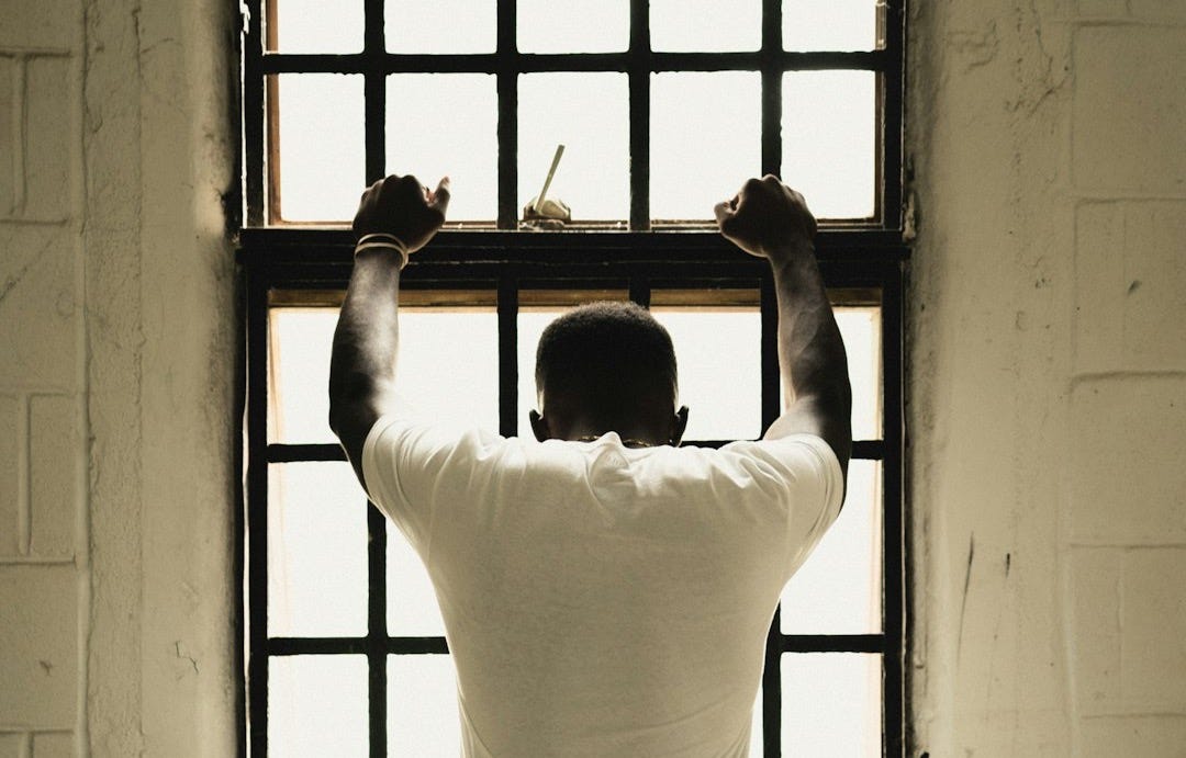 man in white t-shirt standing in front of window