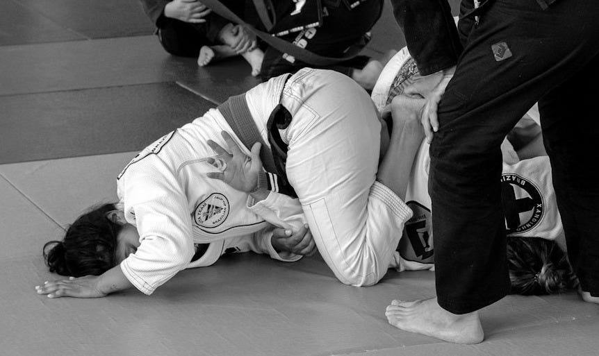 a group of people standing around a person on a mat a group of people standing around a person on a mat