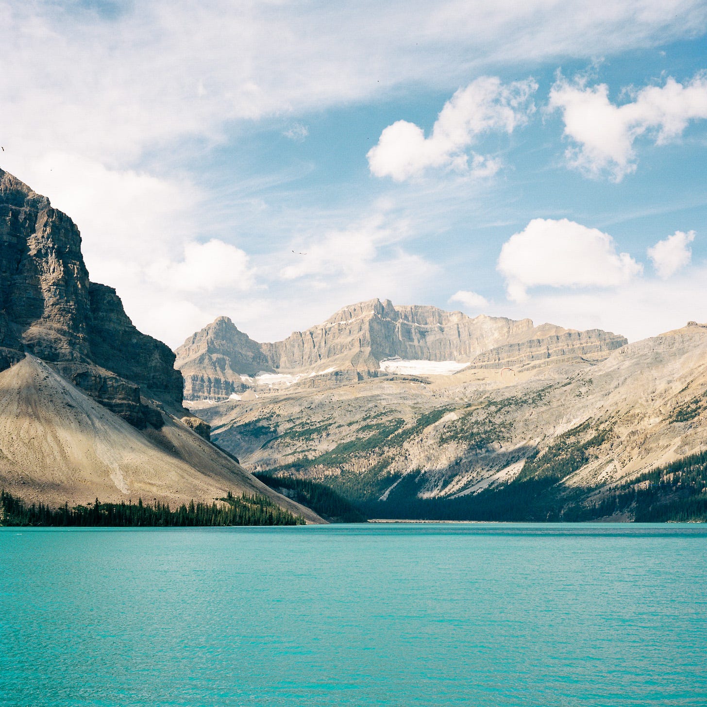 Photo of mountains towering over a light blue lake