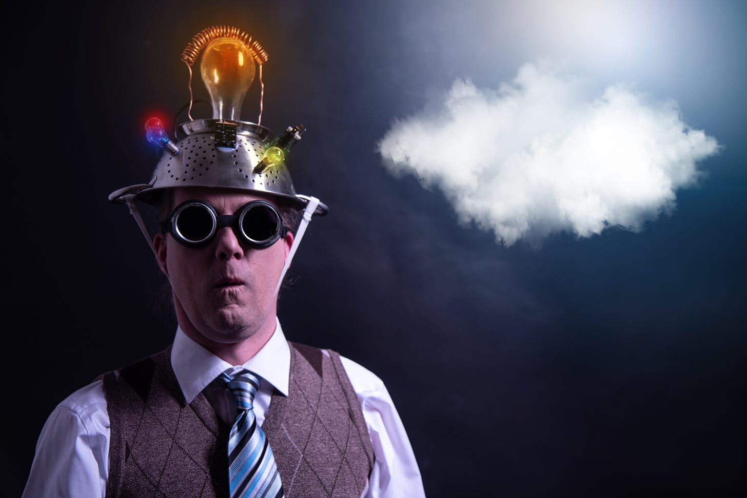 A cloud tries to get away from a man wearing goggles with a colander on his head.