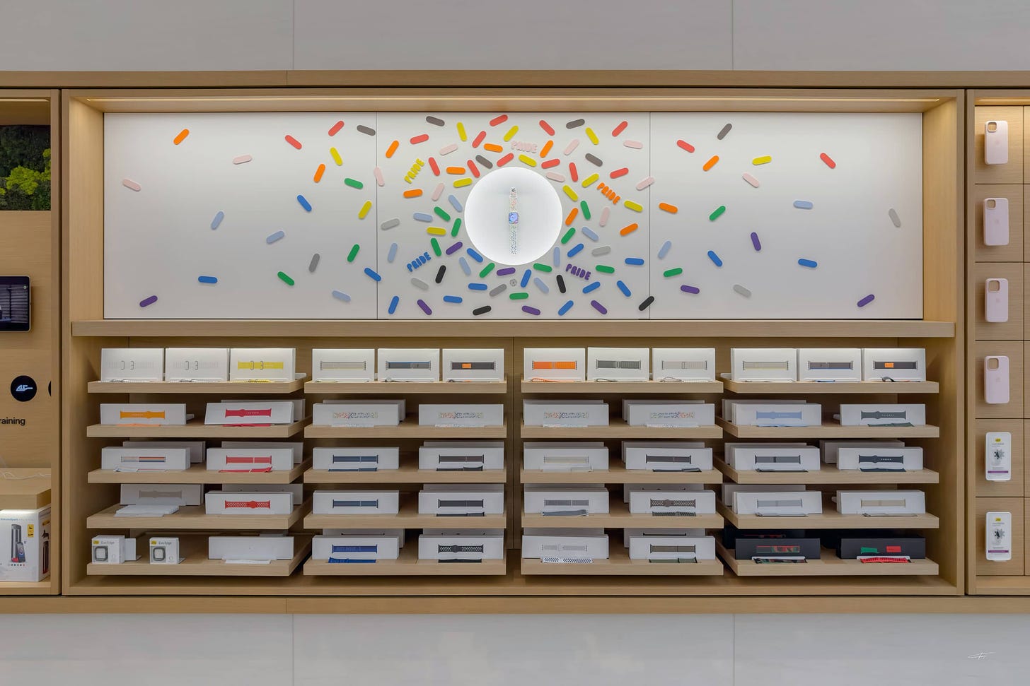 The Apple Watch Pride bay at Apple Rosenthaler Straße. Colorful geometric shapes are set against a white background. A single Apple Watch rests in the center.