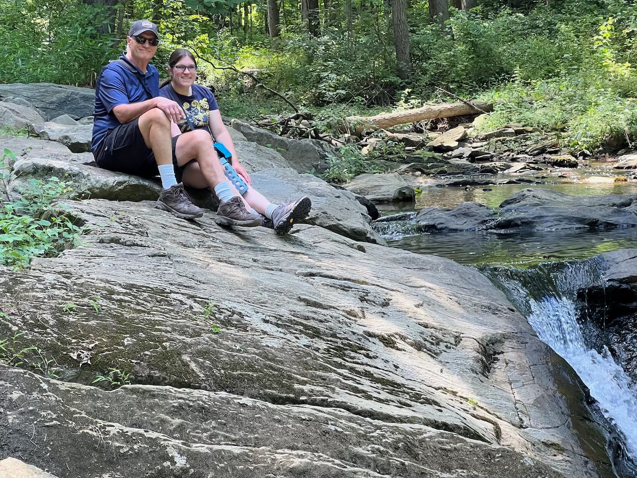 My dad and I (both white) sitting on a rock formation next to a stream