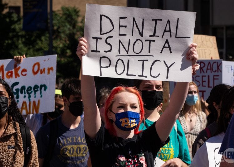 A climate denial protestor holding the sign: "Denial is NOT a policy."
