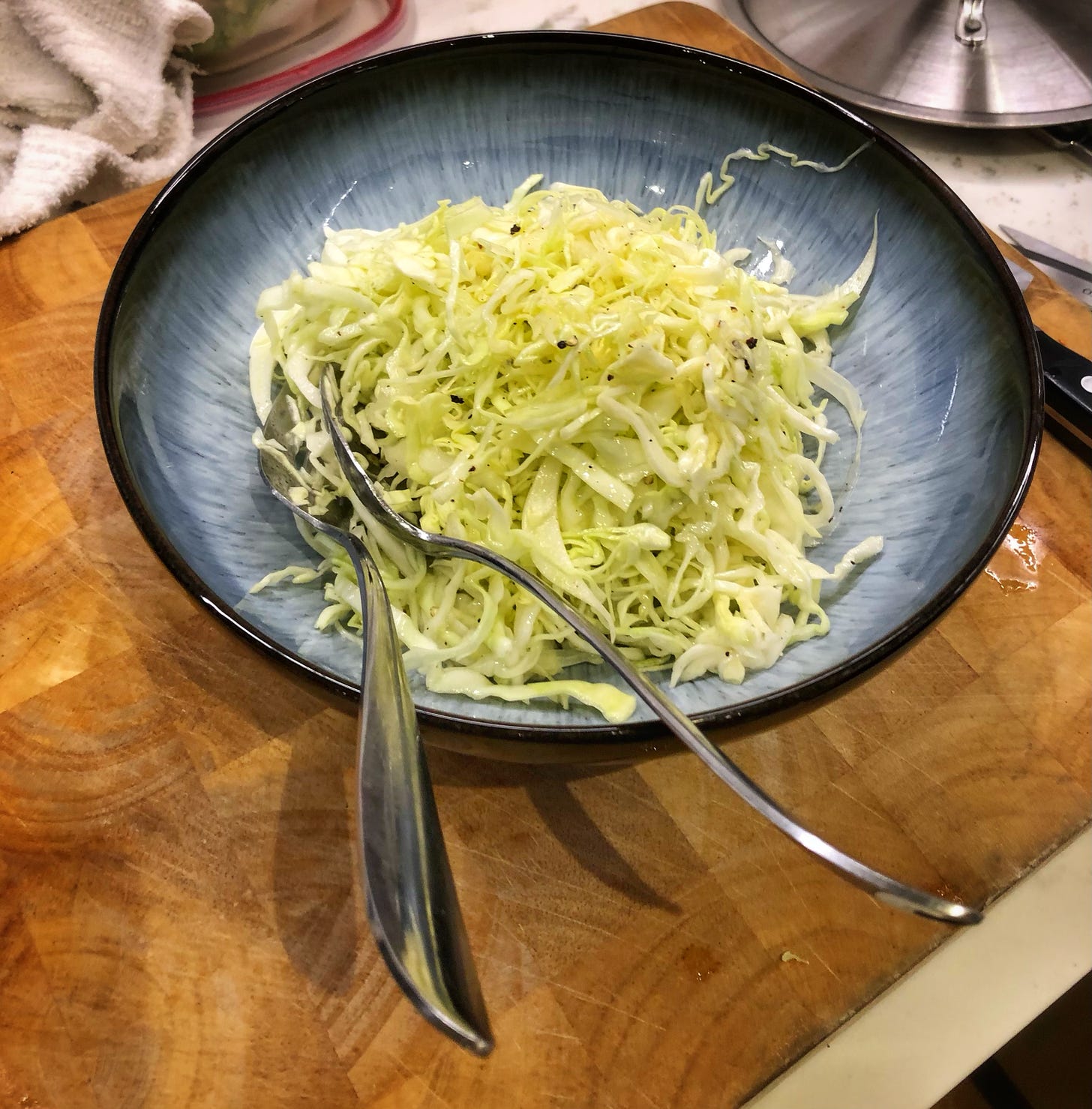 A bowl of Insalate Cappuccio - shredded cabbage, lemon juice, salt, pepper, and olive oil - on a kitchen countertop.