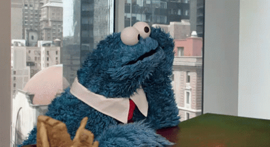 The cookie monster tapping their fingers on a table waiting