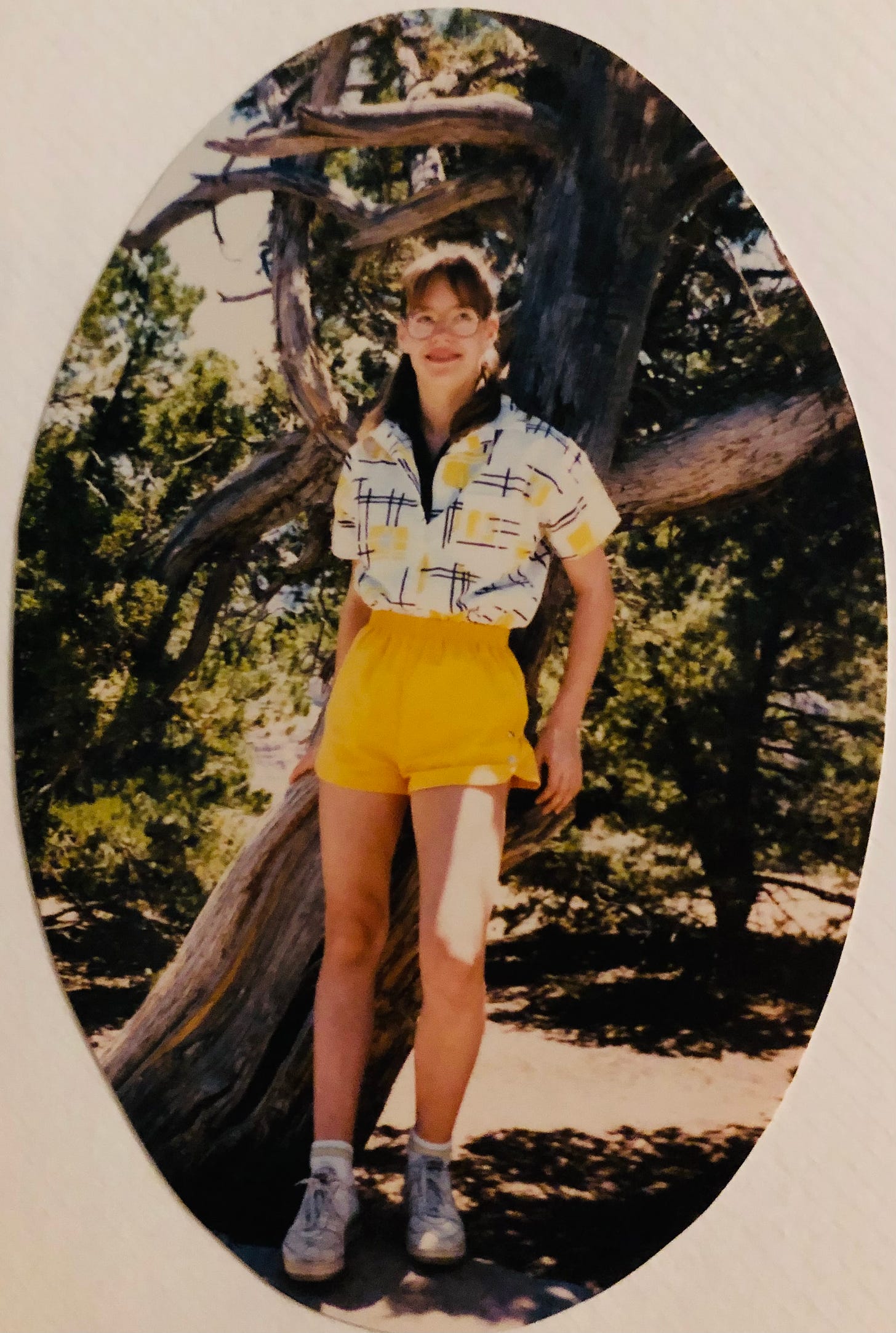 The author at 13 in big glasses, braces, canary yellow shorts, grungy sneakers, and two shirts--black under a white-black-and-yellow slashy 80s geometrical design. Both collars flipped up. Of course.