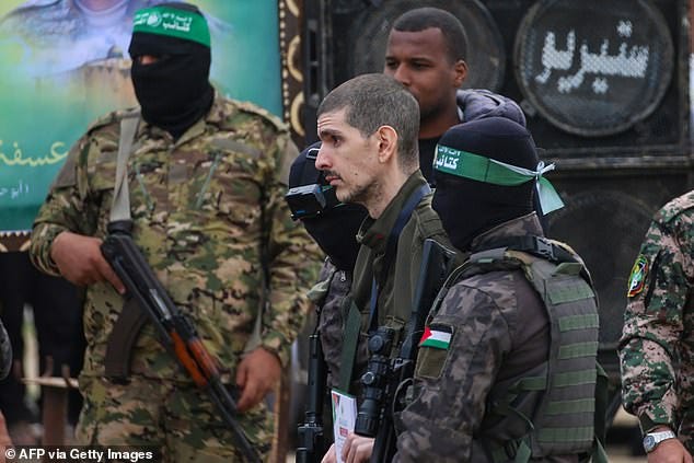 Hamas fighters escort Israeli hostage Or Levy on a stage before handing him over to a Red Cross team in Deir el-Balah, central Gaza, on February 8, 2025, as part of the fifth hostage-prisoner exchange of a fragile ceasefire