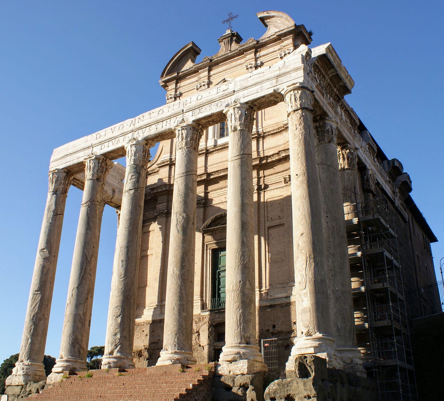 An ancient Roman building, fronted by six large classical columns, topped with a Christian cross.