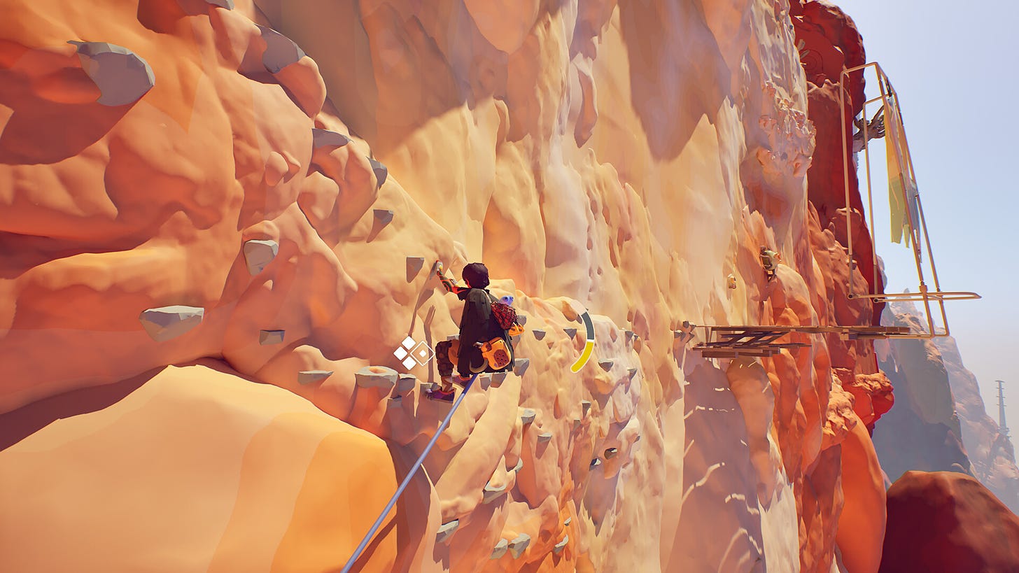 A person climbing on a sandy rockface, with wooden structures in the distance