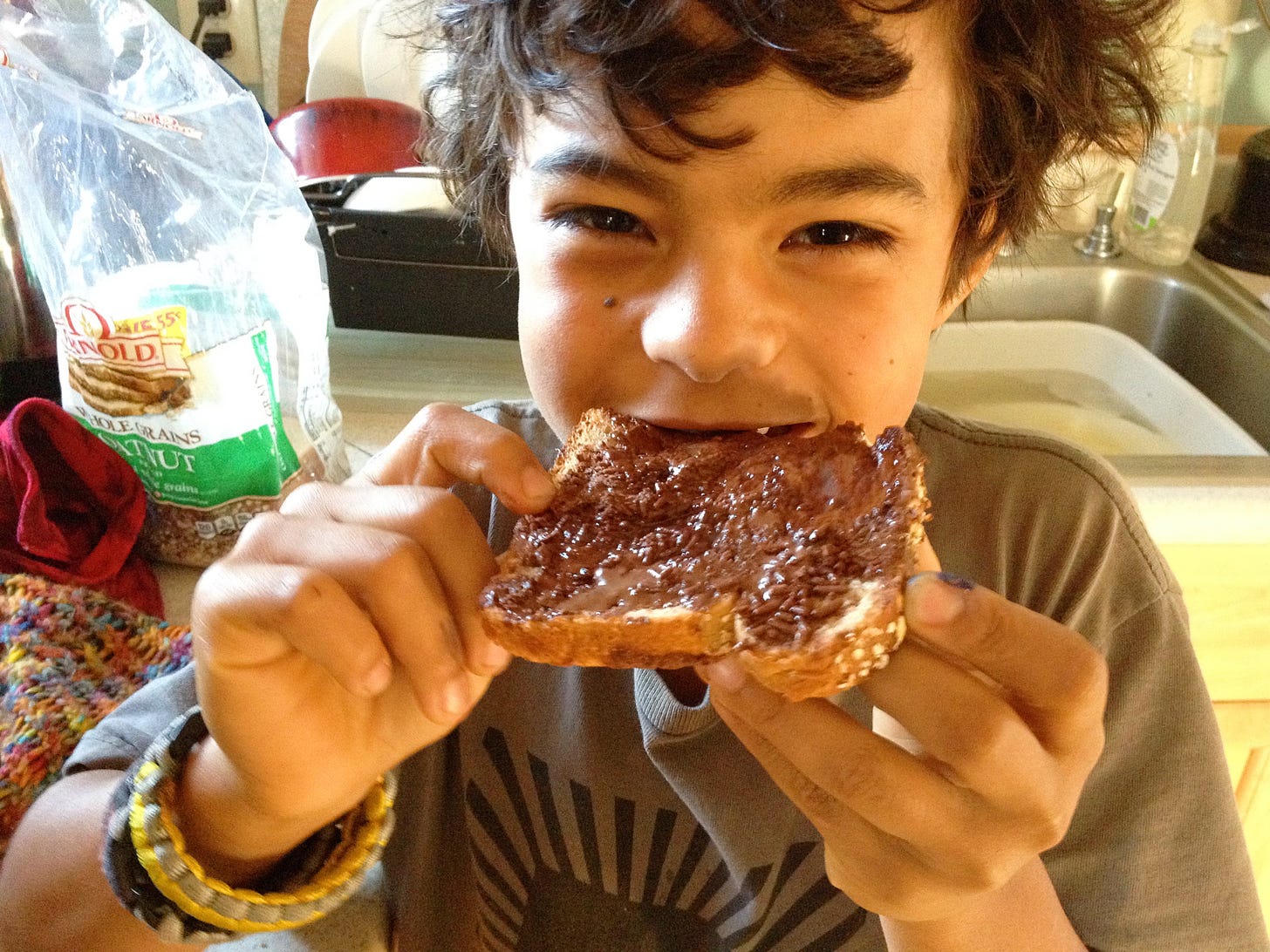 happy kid eating bread spread with Nutella