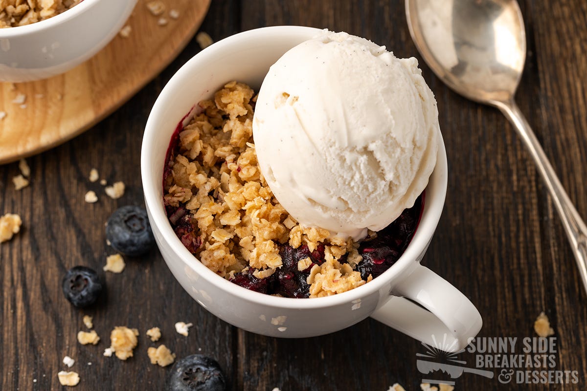 Blueberry crisp in a mug with ice cream.