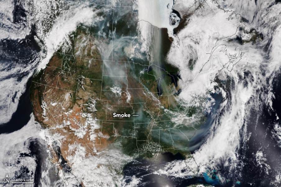 Brown and gray smoke from Canada streams across the U.S. down to northern Florida. Clouds occupy much of the scene.