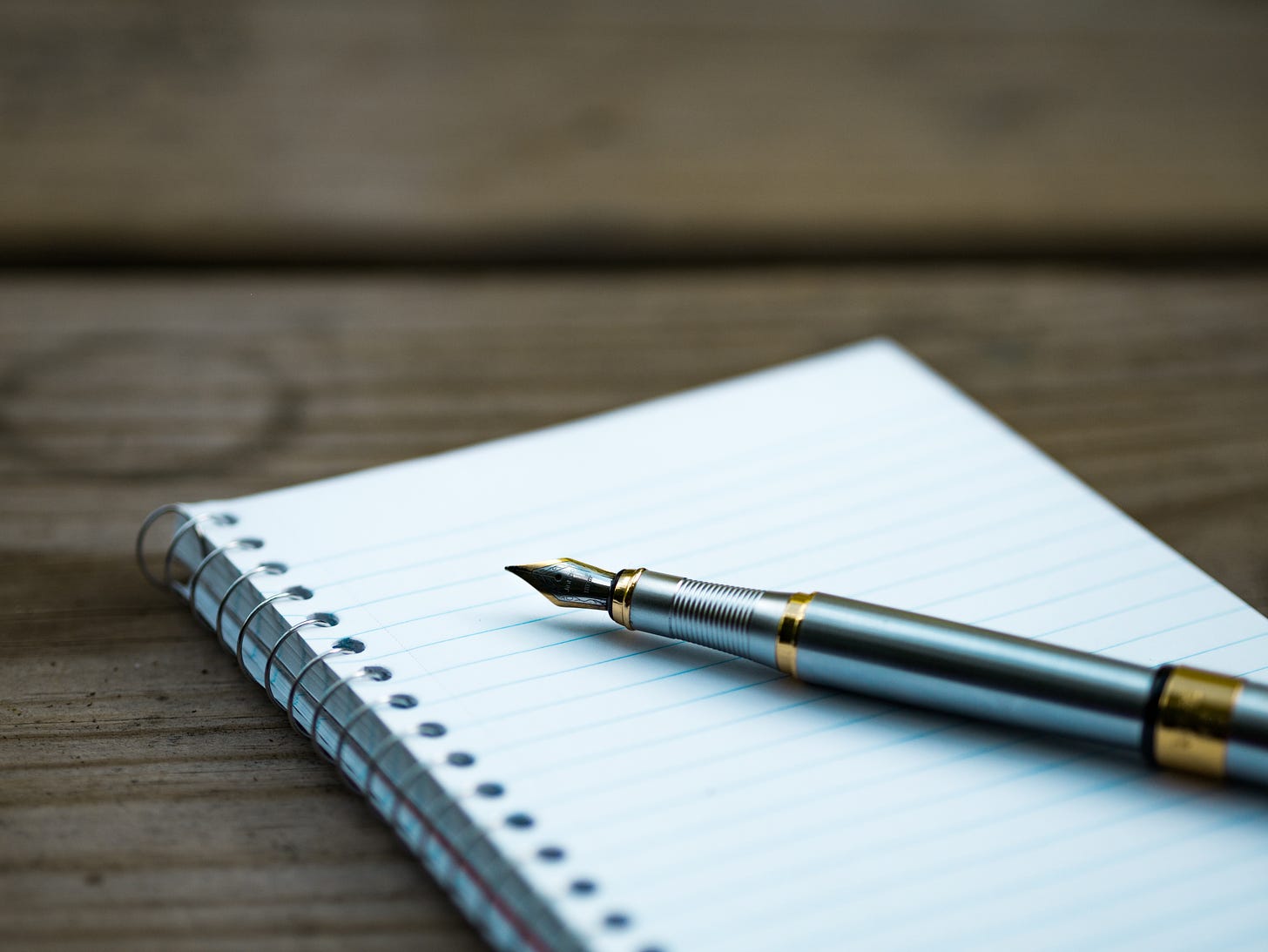 Photograph of a journal with lined paper and a fountain pen
