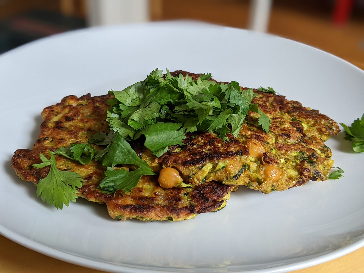 courgette, chickpea and herb fritters on a place with coriander on top