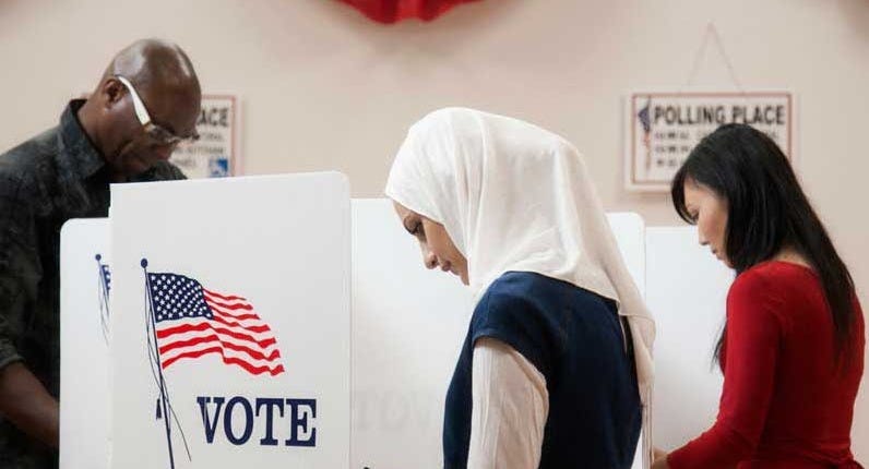 A woman wearing a white hijab at the voting booth