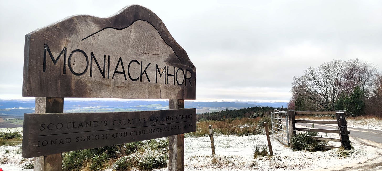 A wooden sign saying Moniack Mhor: Scotland's Writing Centre on it in front of a snowy landscape