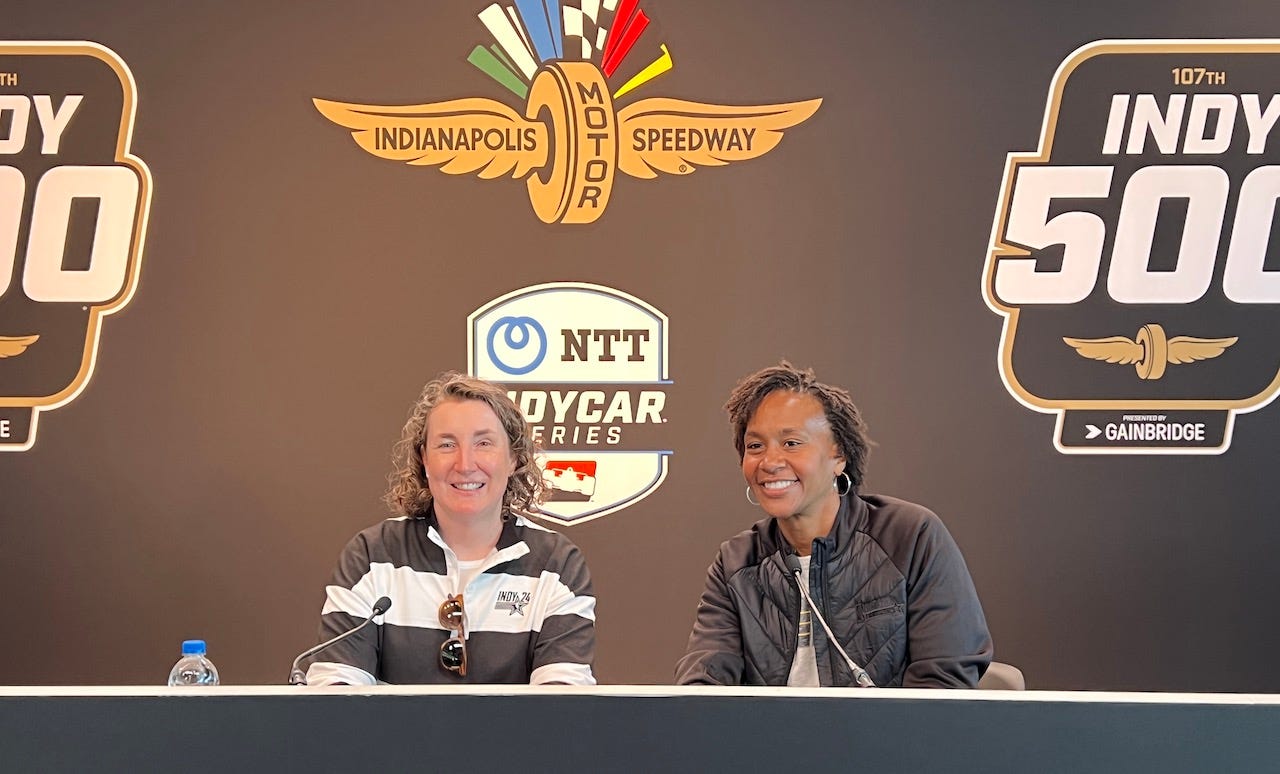 Mel Raines and Tamika Catchings sit at the press conference table with a backdrop filled with logos of IMS and the Indy 50.