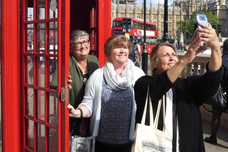 Three women taking a selfie outside a Westminster red phone box