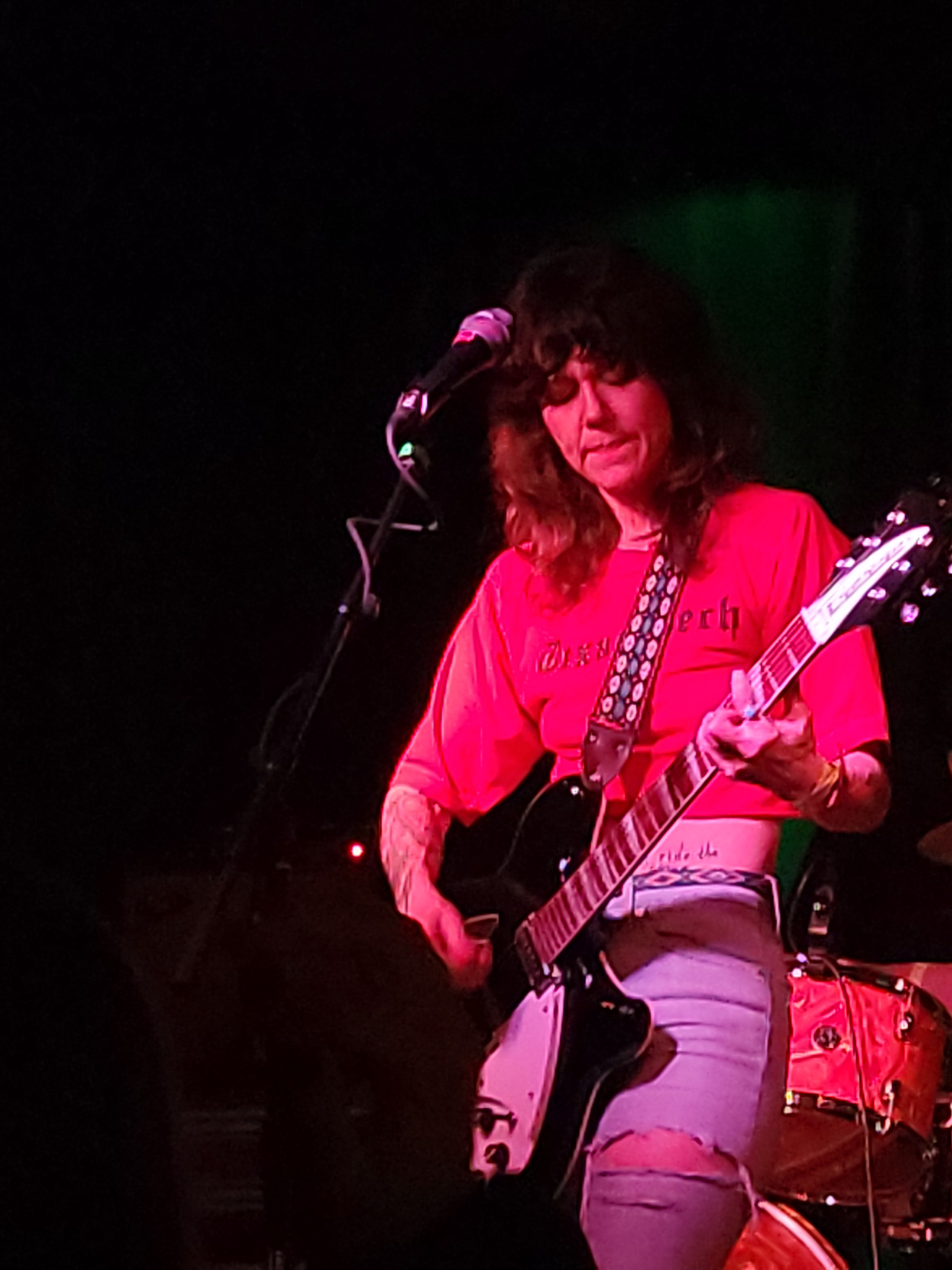 Lilly Hiatt in red shirt, playing guitar