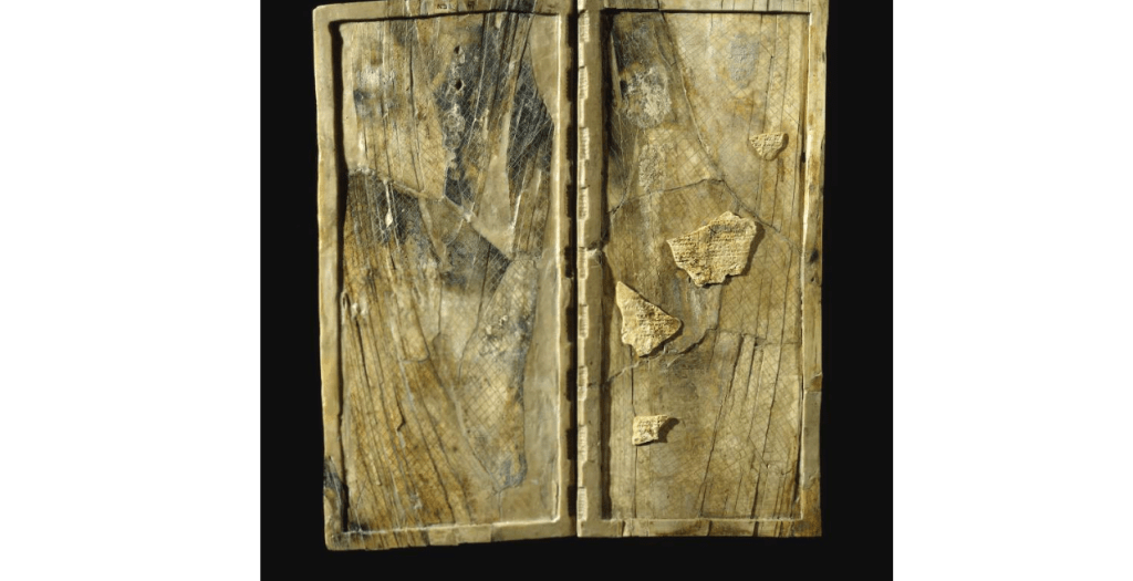 color photograph from a museum catalog.Waxed ivory writing tablet: one of a set of sixteen writing tablets hinged together as a folding set. It is scored on the back and front to receive the wax surface, which would have been inscribed in cuneiform with a stylus.