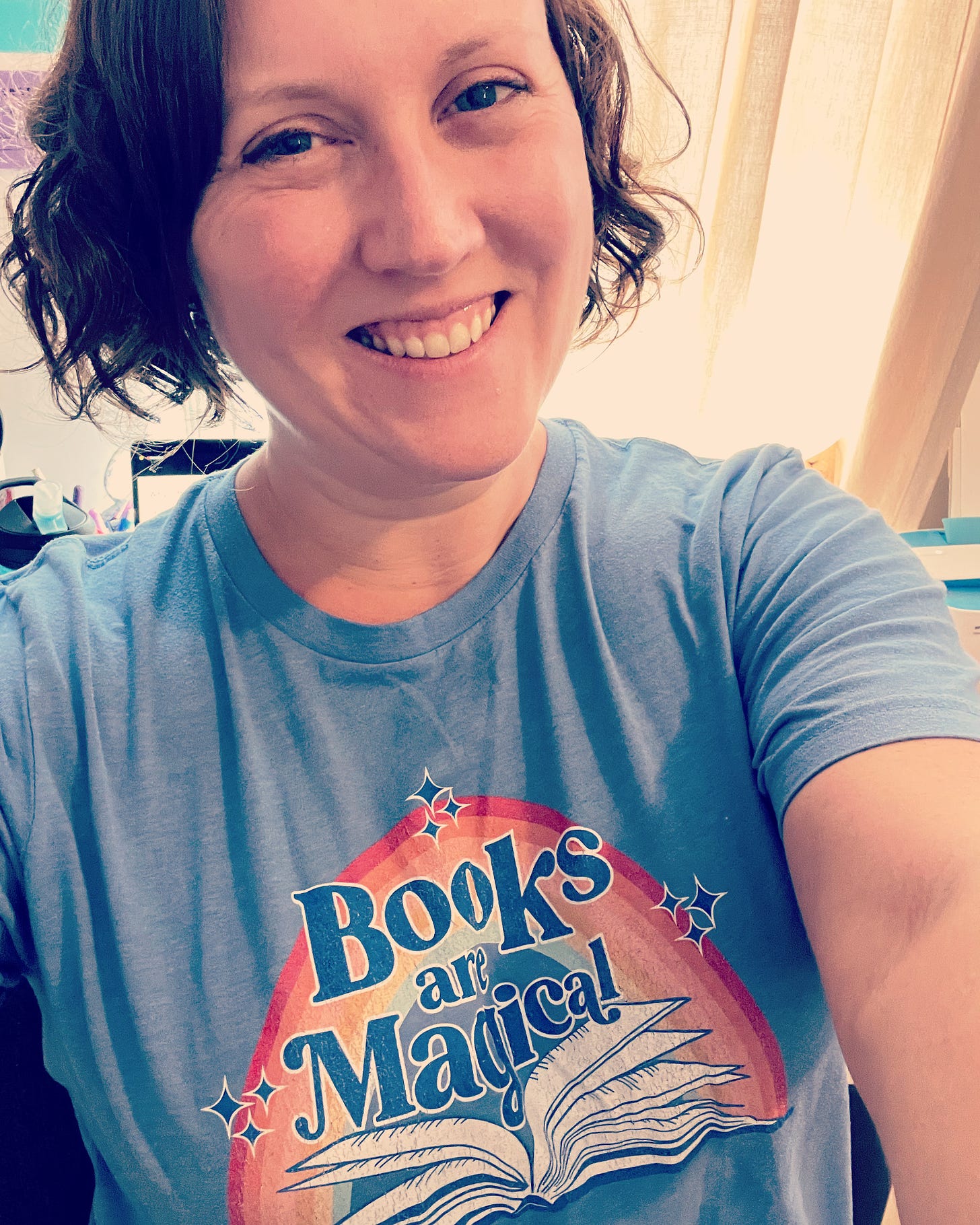 Me wearing a "Books are Magical" shirt, smiling proudly
