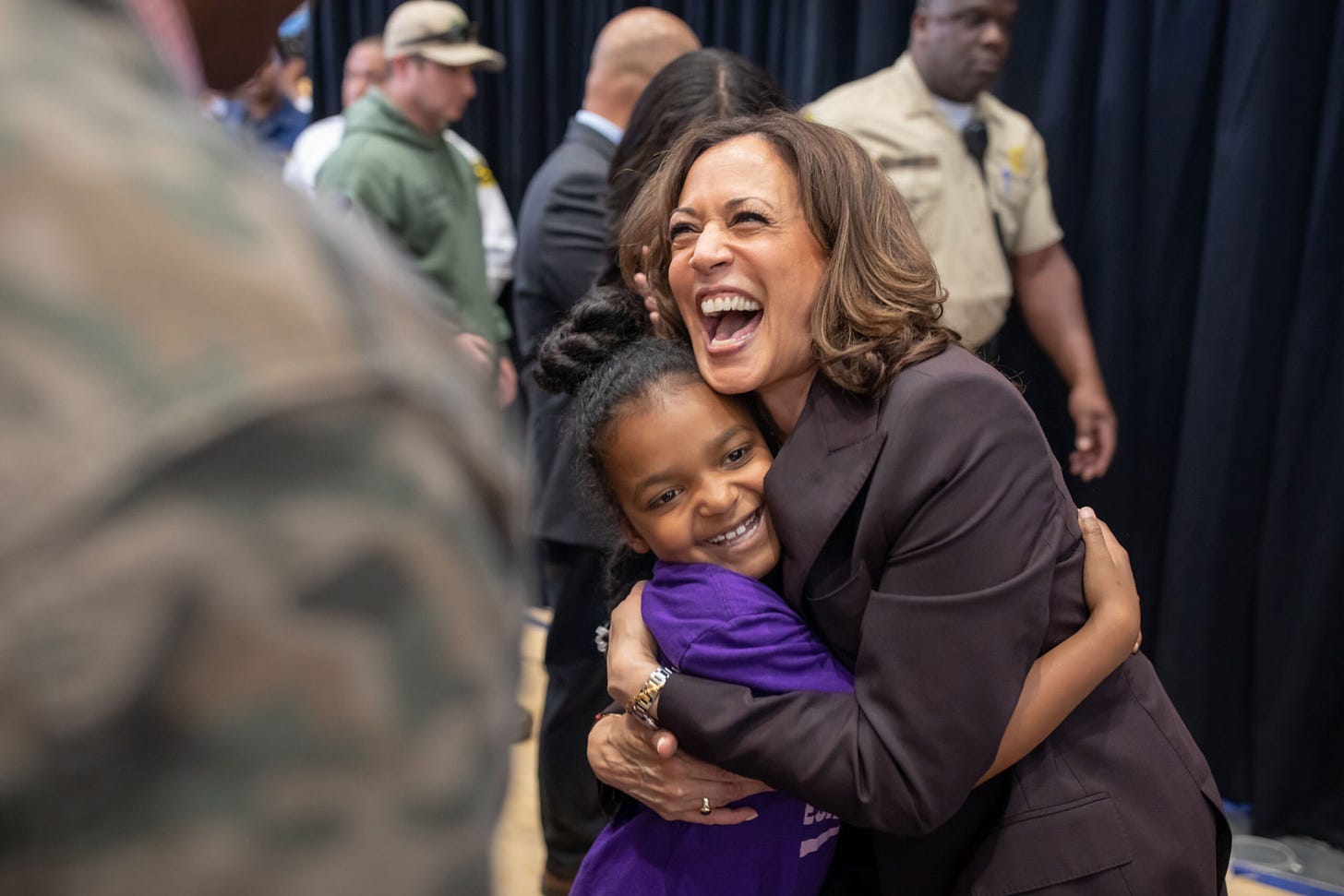 A jubilant Harris embraces a smiling young girl in a purple t-shirt